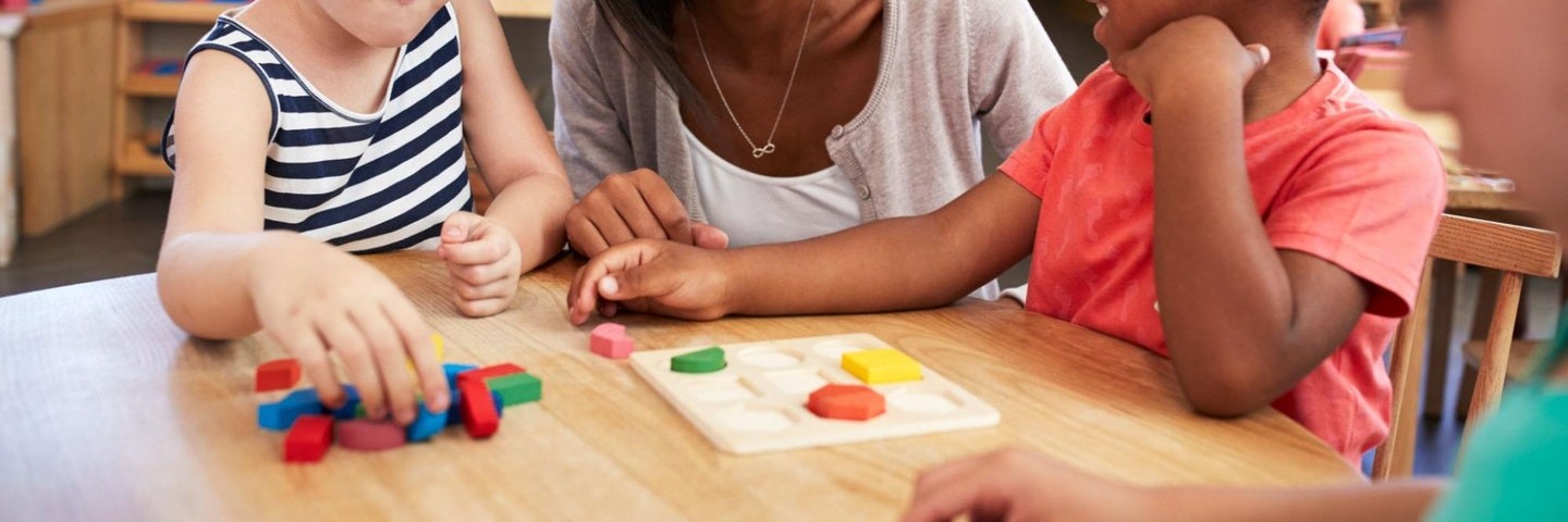 A teacher and two students use wooden blocks to do geometry activities.