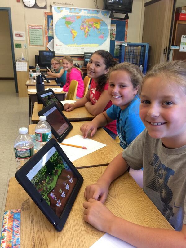 Five students are smiling and playing Prodigy game