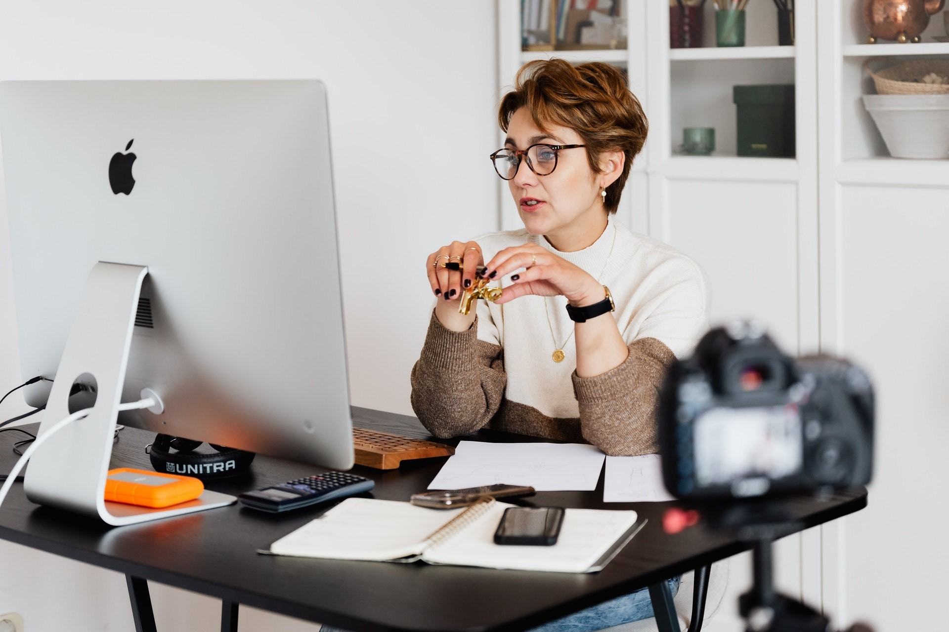 Female teacher sits at workstation with a camera set up to teach online.