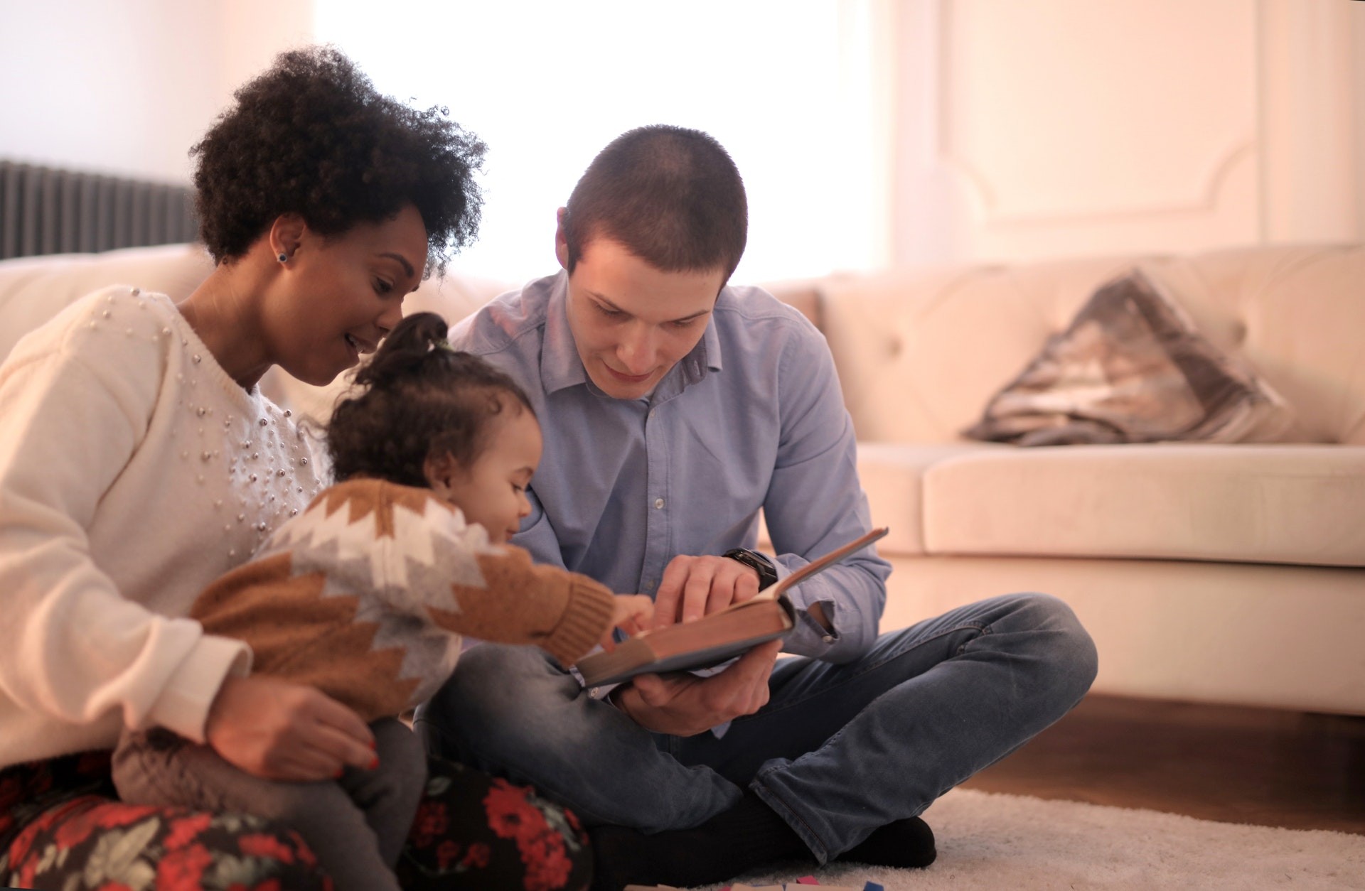 Two parents read with their daughter at home.