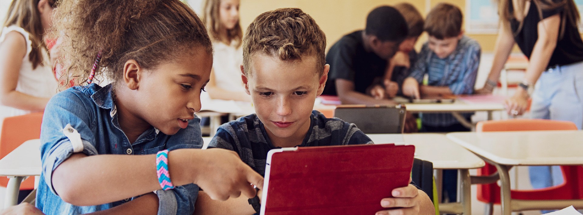 Two students read together on a tablet