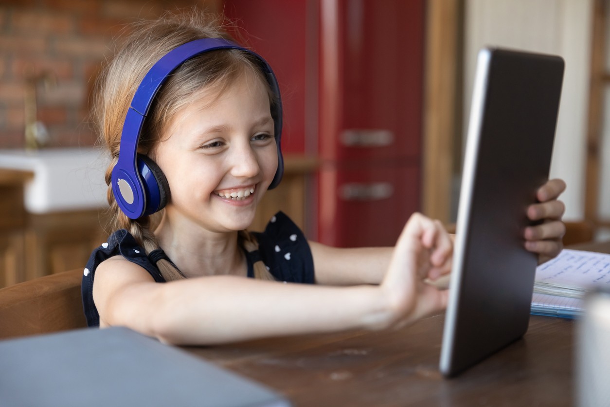 Child smiling while playing Prodigy on her tablet.