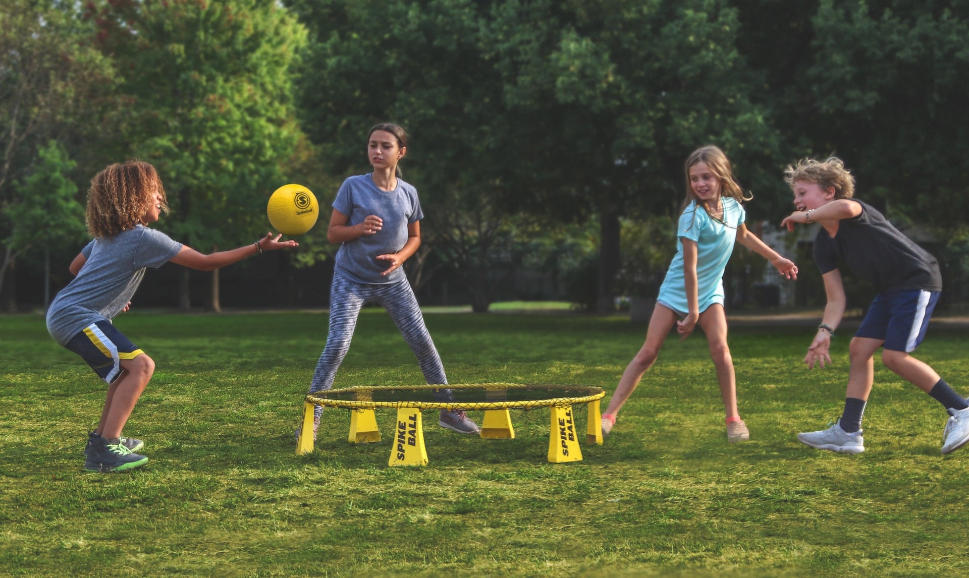 A group of kids plays spikeball outside at a playdate. 