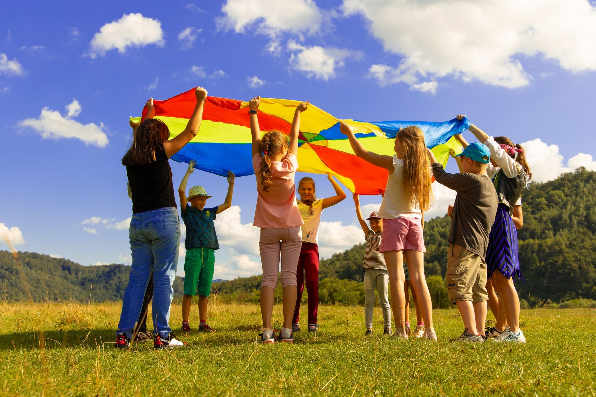 A group of students stands outside holding a colorful circle of fabric as they play active classroom games.