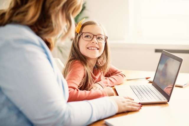 Mother and child smiling in front of a laptop.