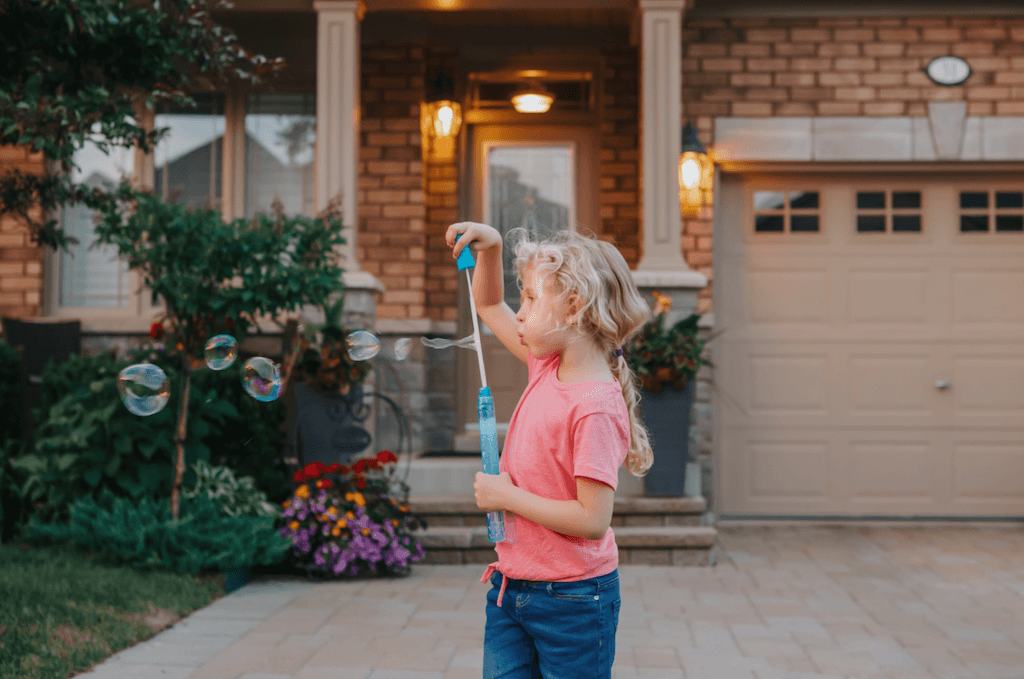 Child blowing bubbles outside during downtime from her homeschooling program 