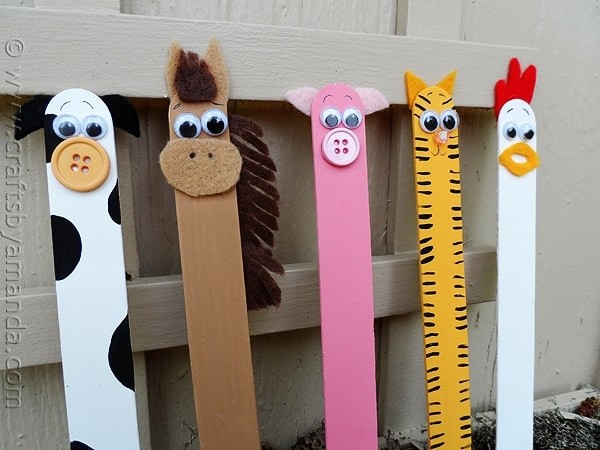 Row of popsicle sticks decorated as farm animals: a cow, horse, pig, cat and rooster.
