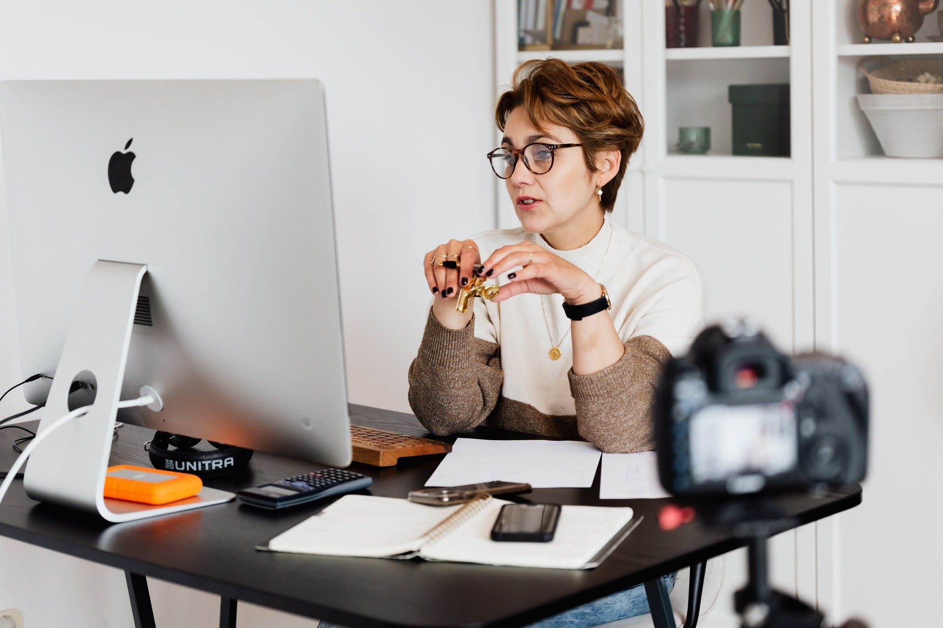 Female teacher sits at workstation with a camera set up to teach online. 