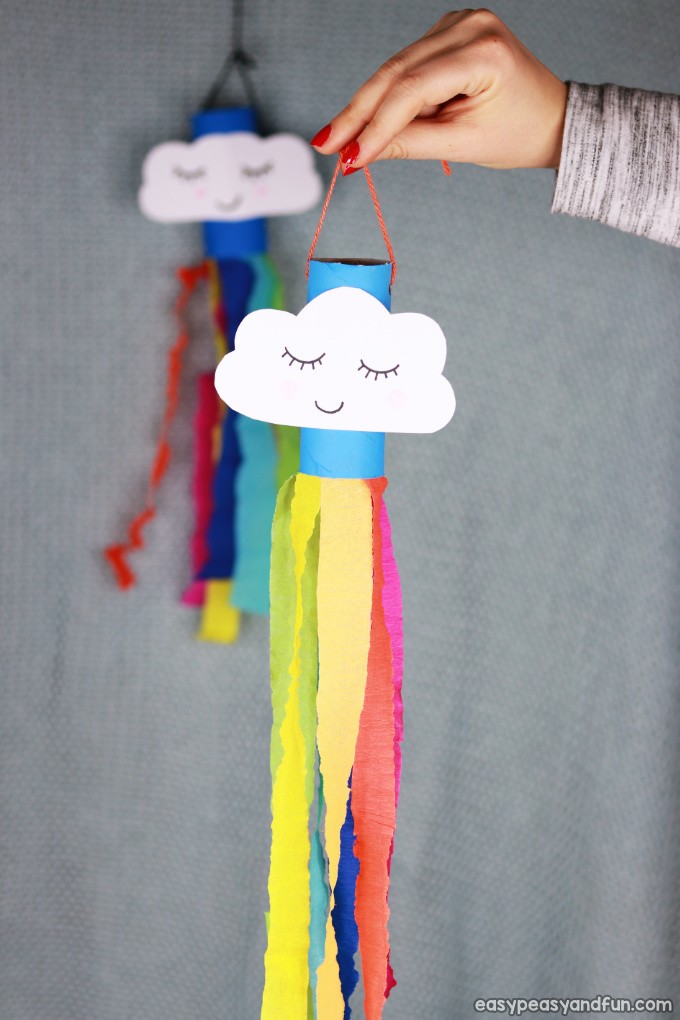 Rainbow windsock craft made from a blue painted toilet paper roll with a smiling cloud. 