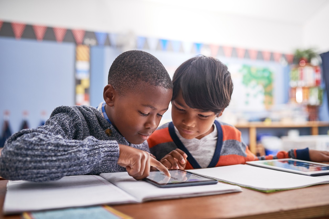 Two kids using Prodigy together on a tablet in class.