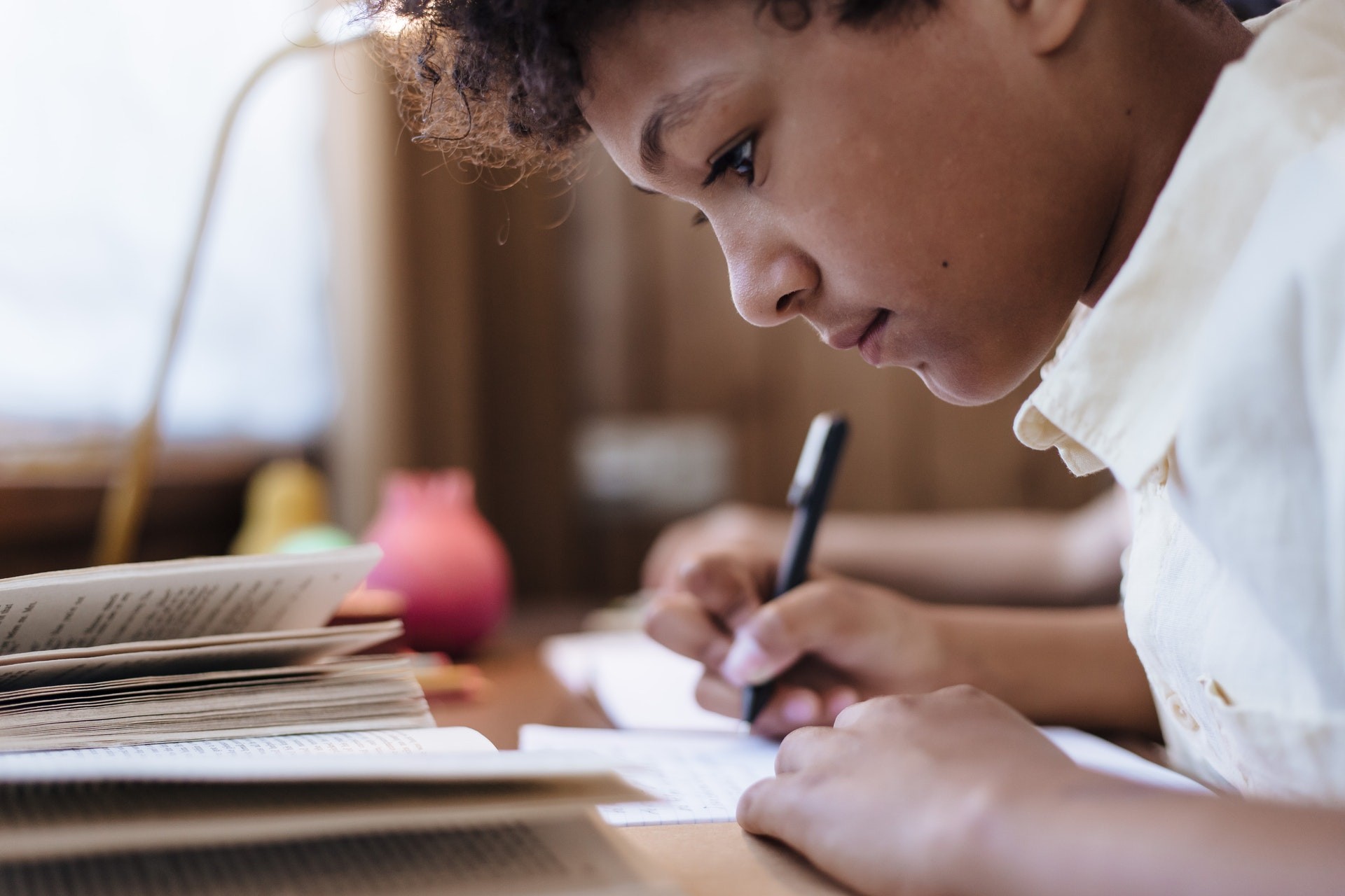 Young boy works on english language learning skills at home by writing in a notebook. 
