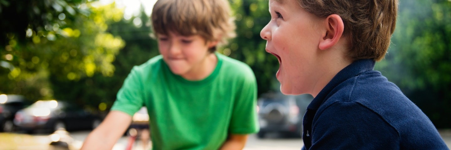 Two young boys smile as they do fun earth day activities outside.
