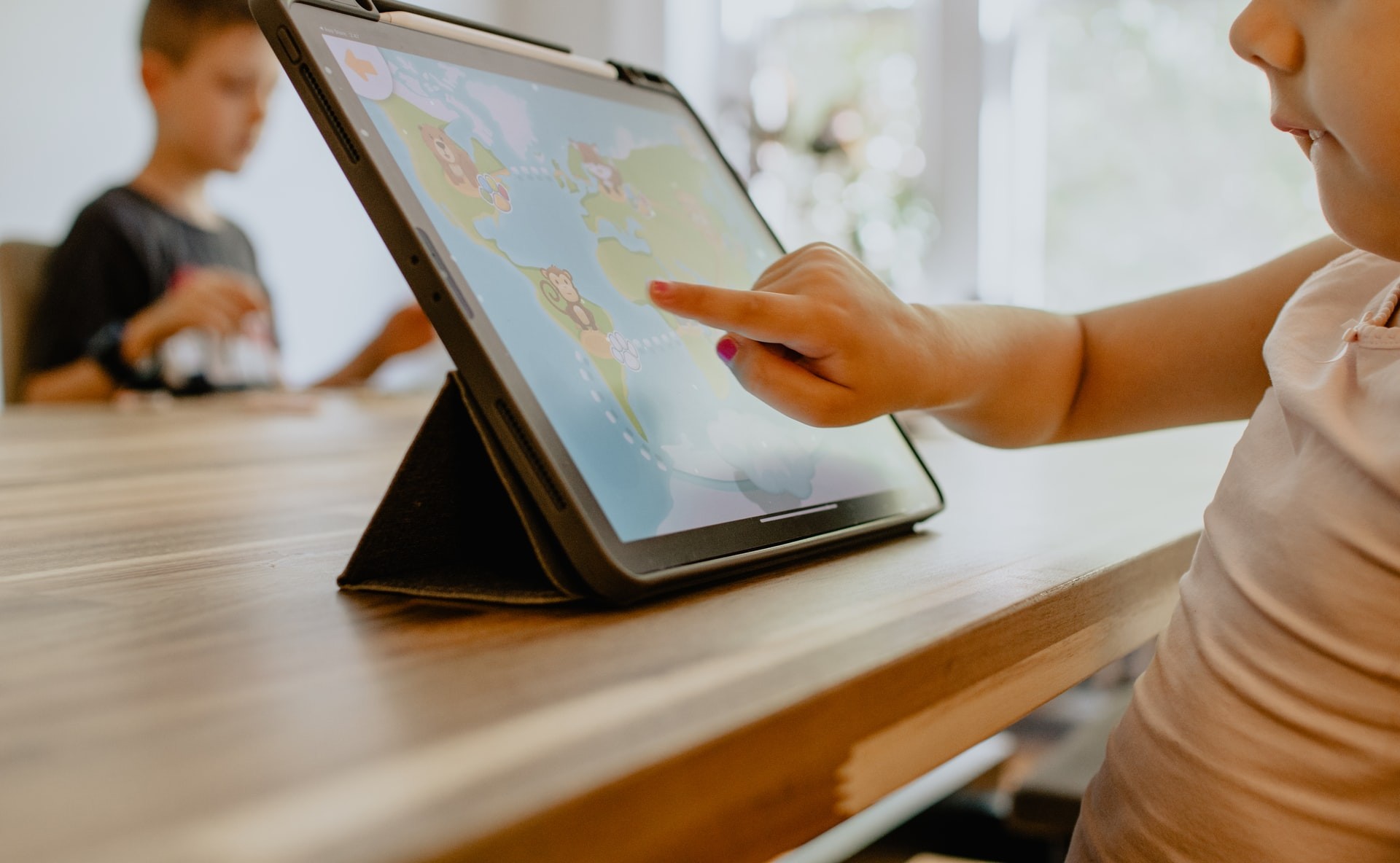 Young student uses a learning app on a tablet while sitting at a table.
