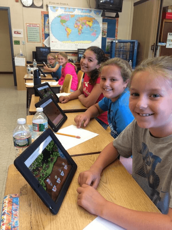 Five students are smiling and playing Prodigy game