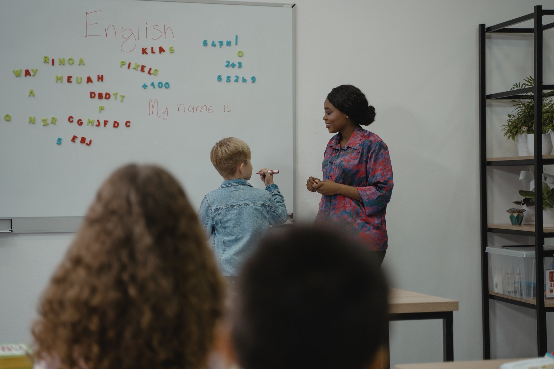 A teacher uses new teaching methods with a student at the whiteboard in english class.
