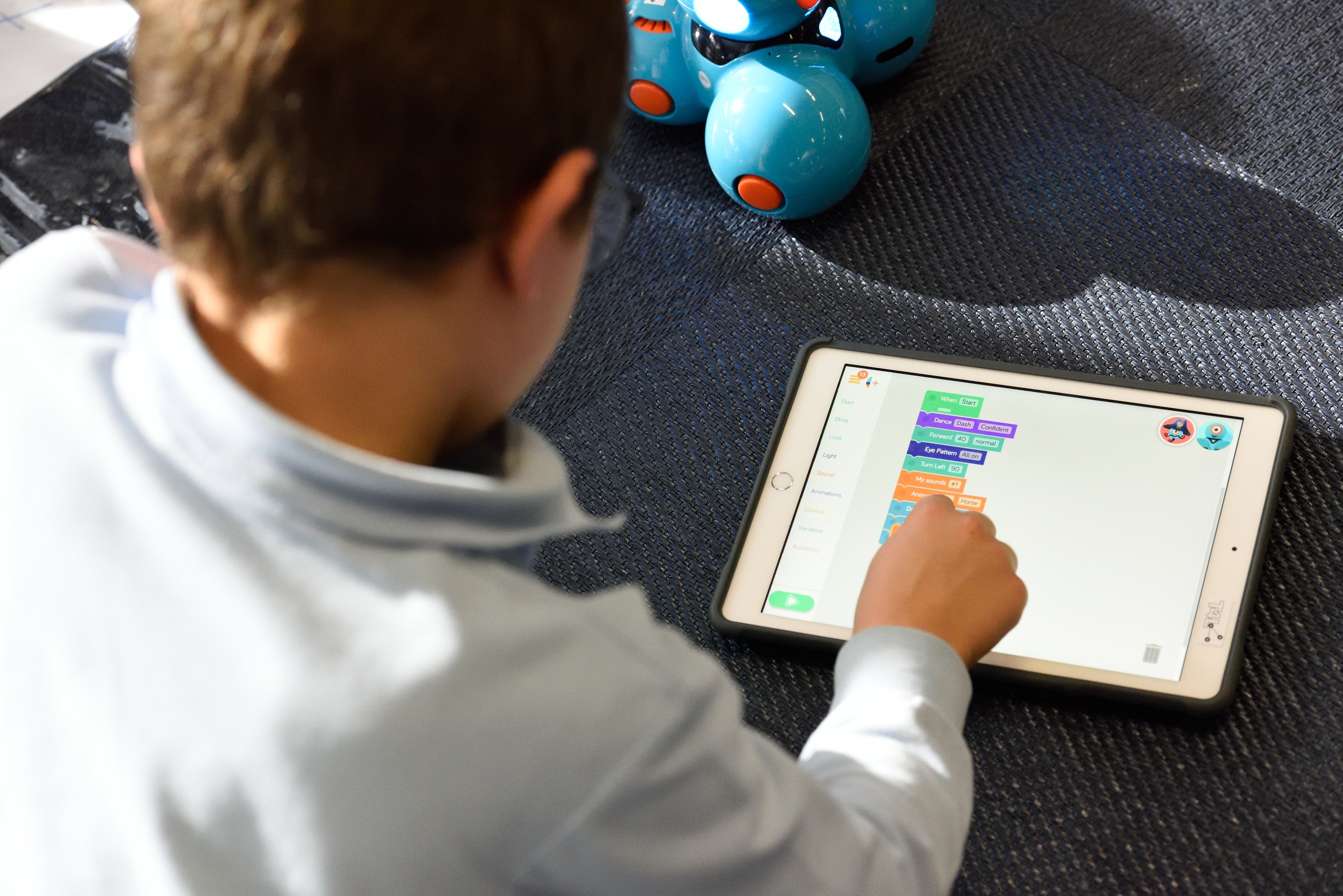 A boy engages in game-based learning on his tablet to complete school work.