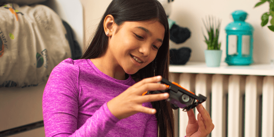 A girl examining a toy car while smiling.