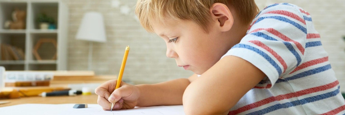 Young boy practices writing activities with a pencil and paper.