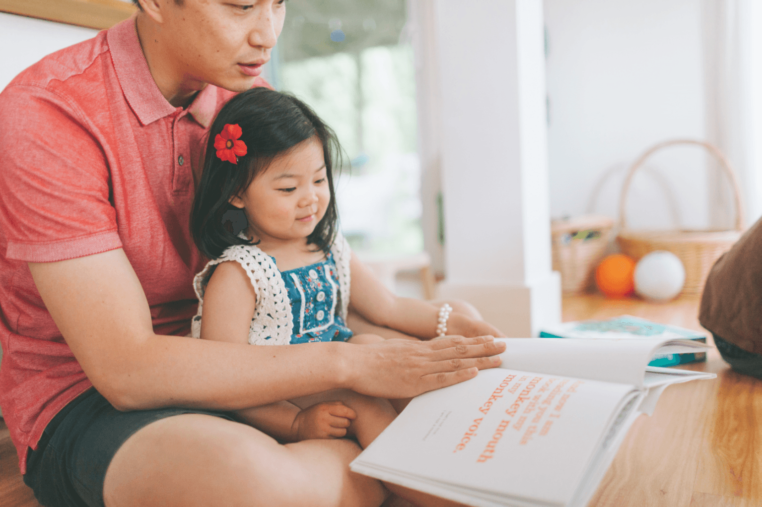 A child and her father reading a book together to assess her reading level before using online reading programs.