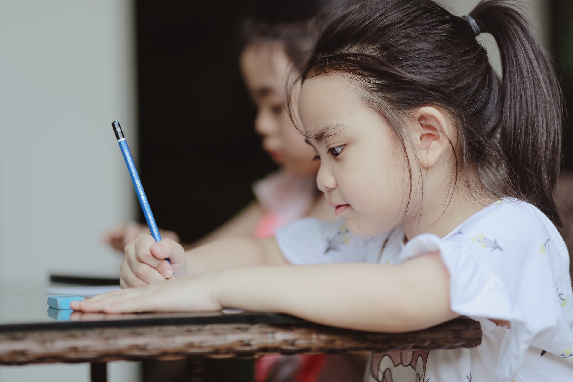 Young girl writes using a paper and pencil during educational activities.