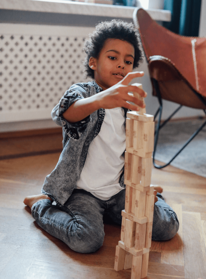 Unschooled child building a tower out of Jenga blocks