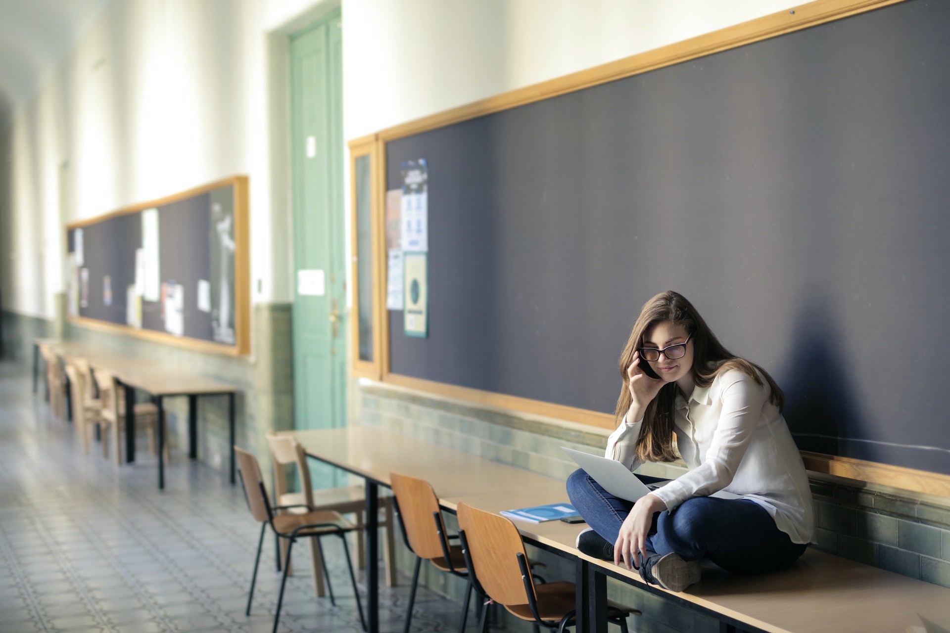 Lone student sitting on a desk in front of blackboards. 