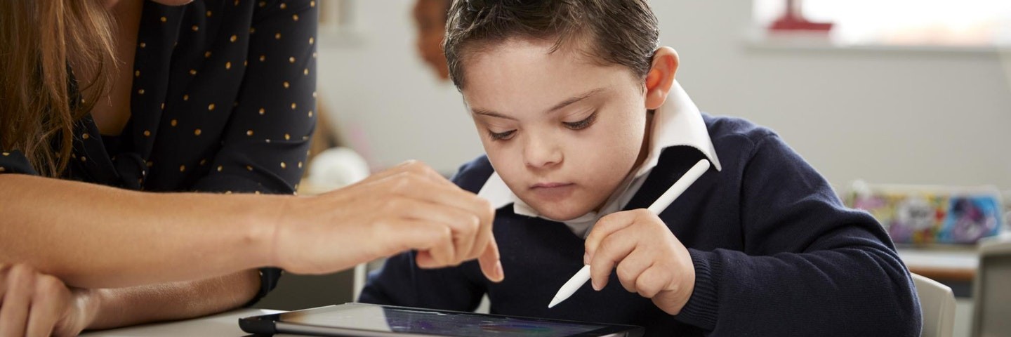 A teacher helps a student complete the Prodigy Placement Test on a tablet.