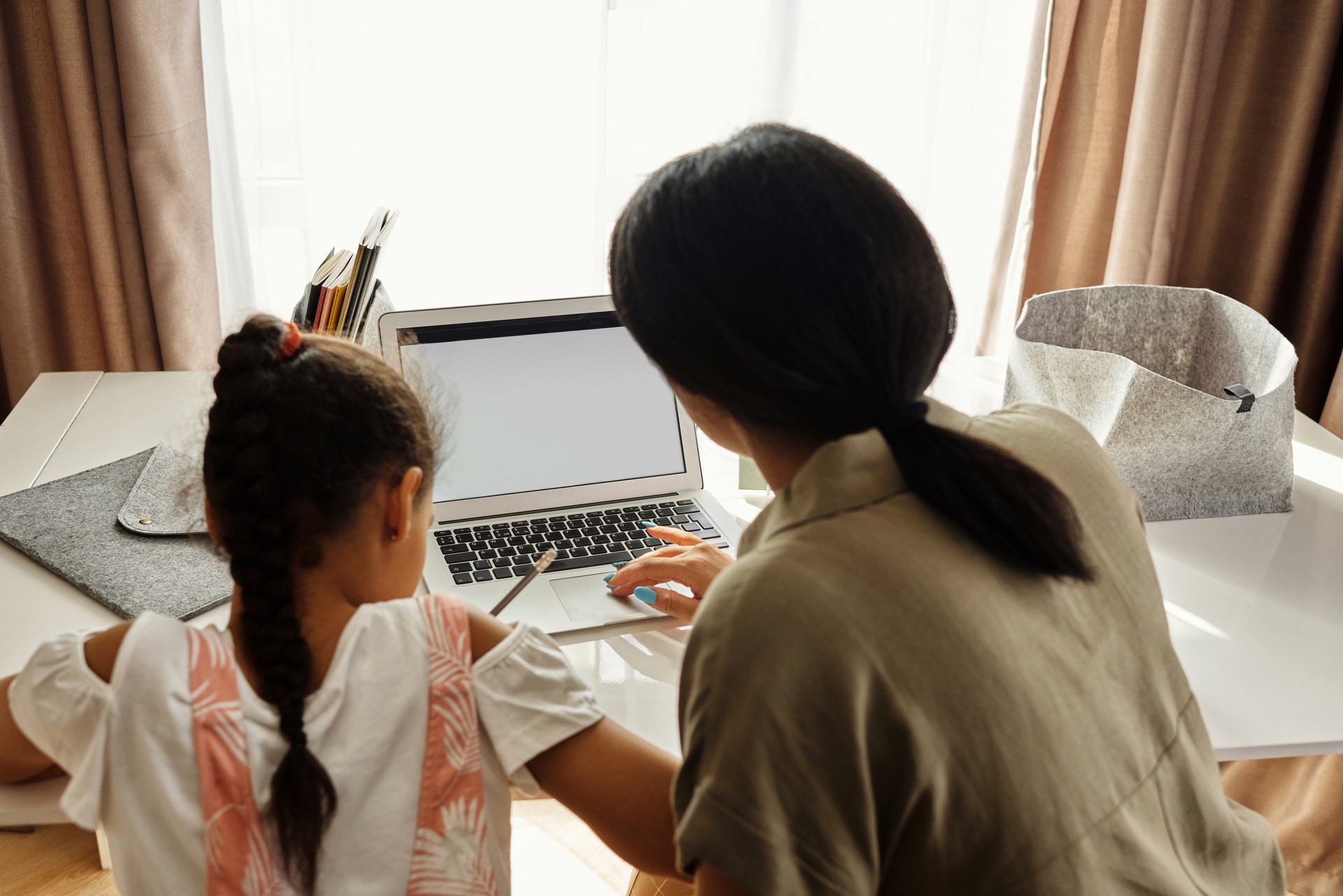 Mother and daughter work at home on a computer to address summer learning loss and unfinished learning.