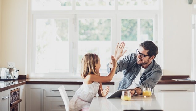 A parent and child give each other a high-five while holding a tablet