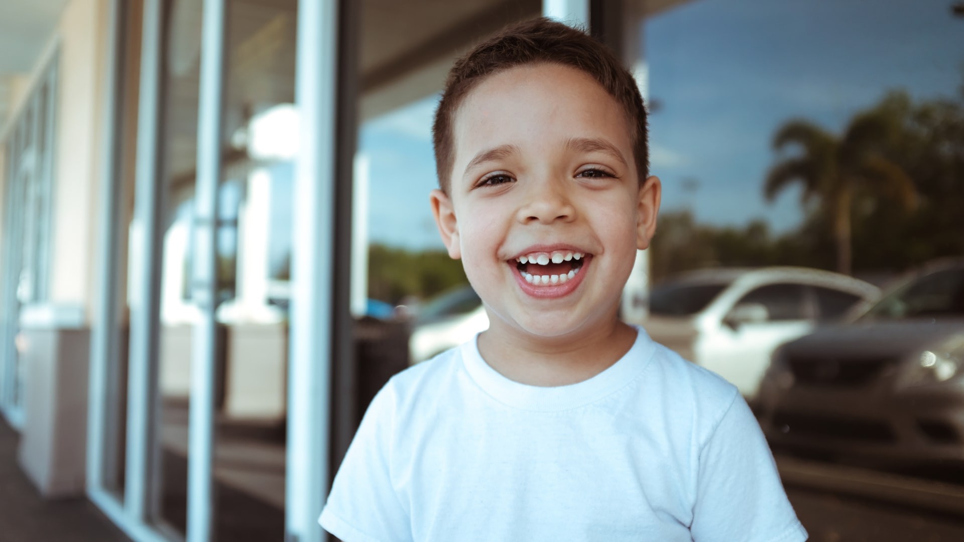 Child smiles while standing outside.