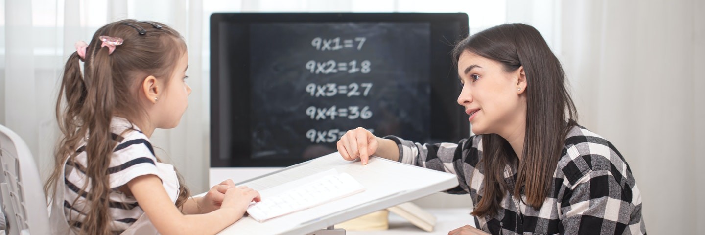 Mom homeschooling math lessons with daughter.