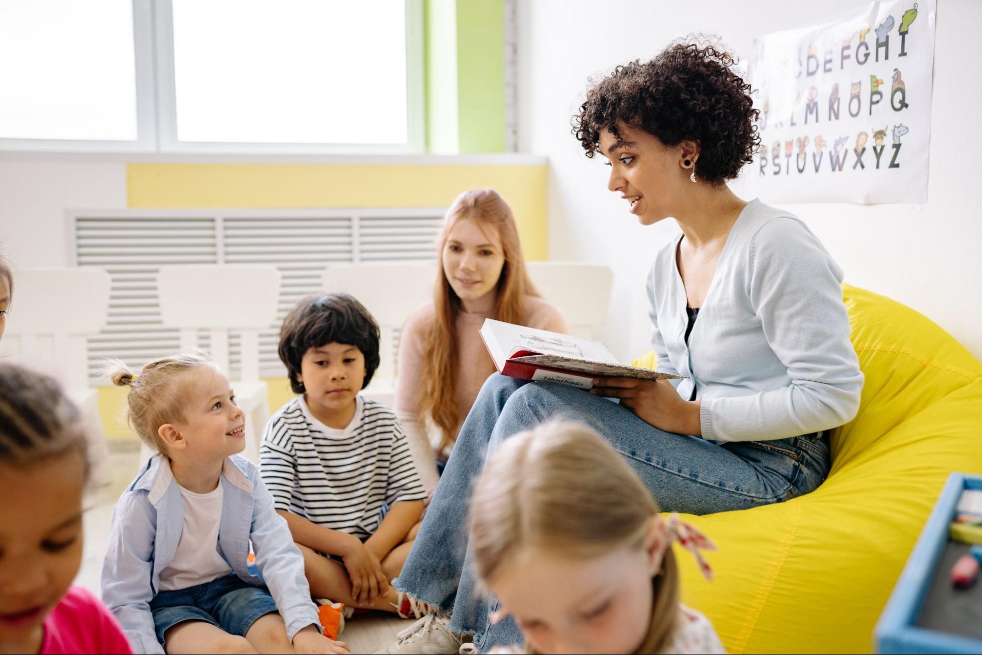 A teacher reads to a group of young students during reading strategy activities.
