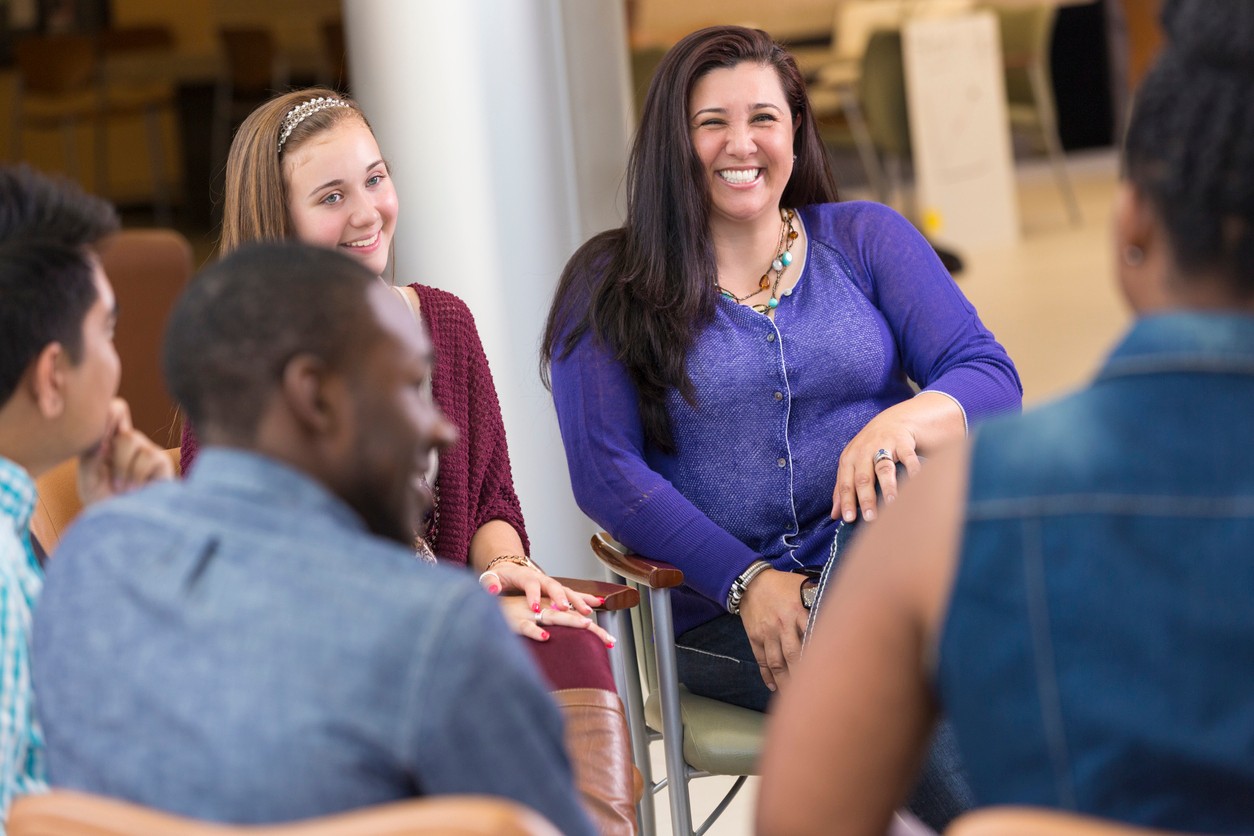 Parent and her daughter smiling in a support group circle for families
