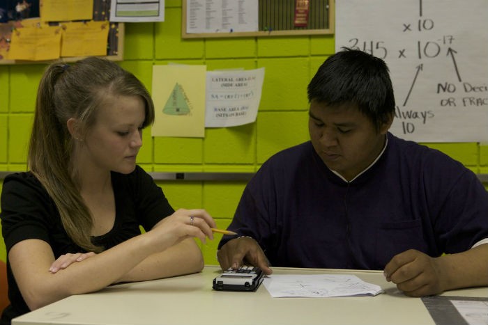 A student with a tutor solving a math problem together.