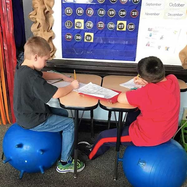 Two students doing school work on a small group table.