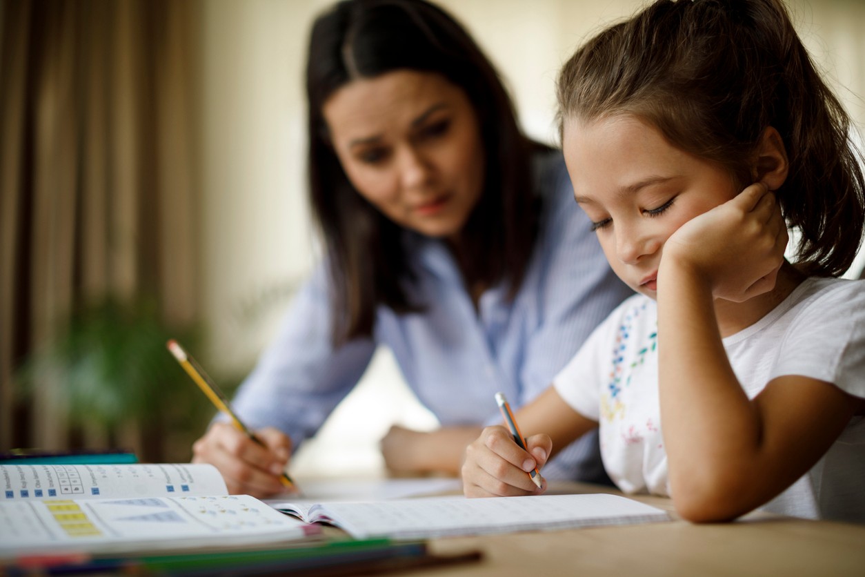 Child looking bored while her mother helps her with homework