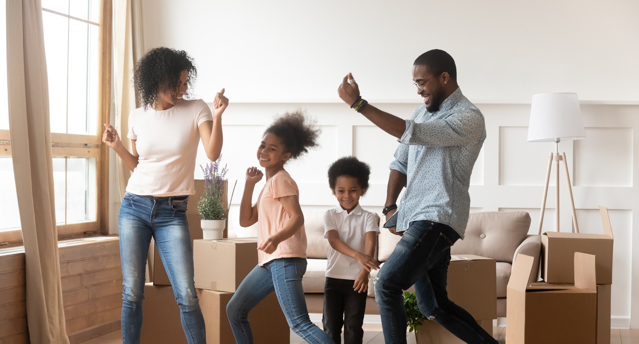 Parents dancing with their two kids in the living room
