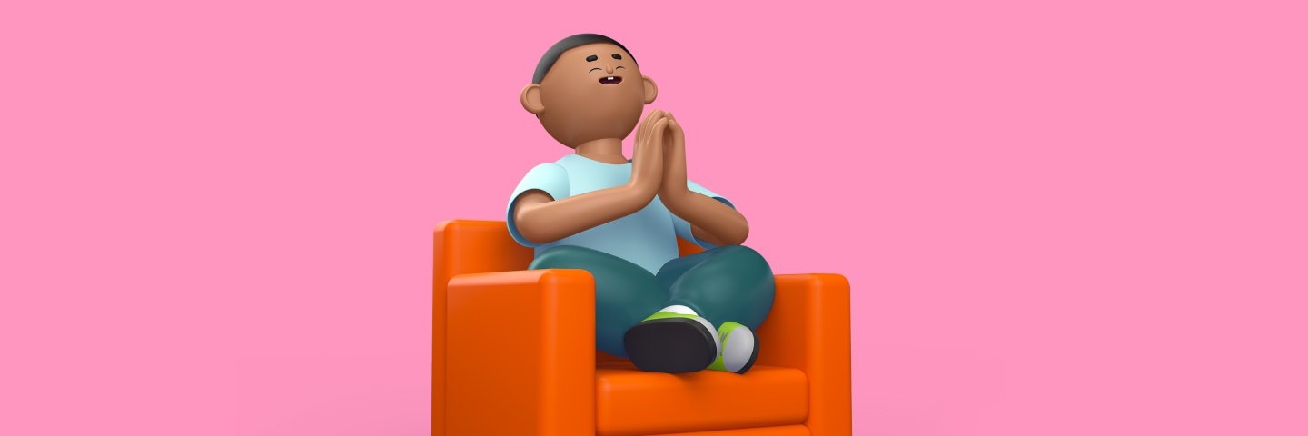 Boy sits on an orange sofa smiling with his hands together.