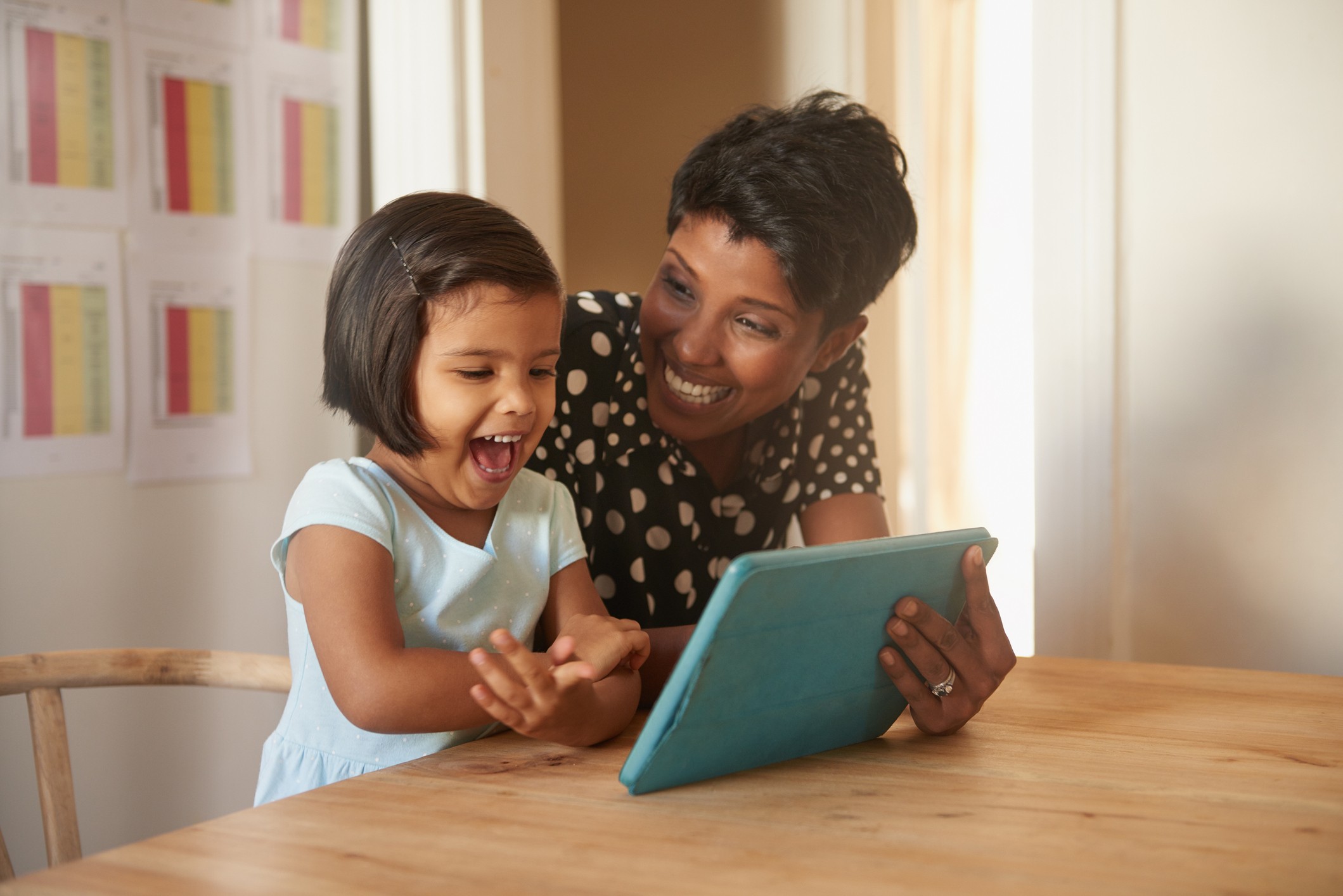 Excited child and parent on a tablet together.