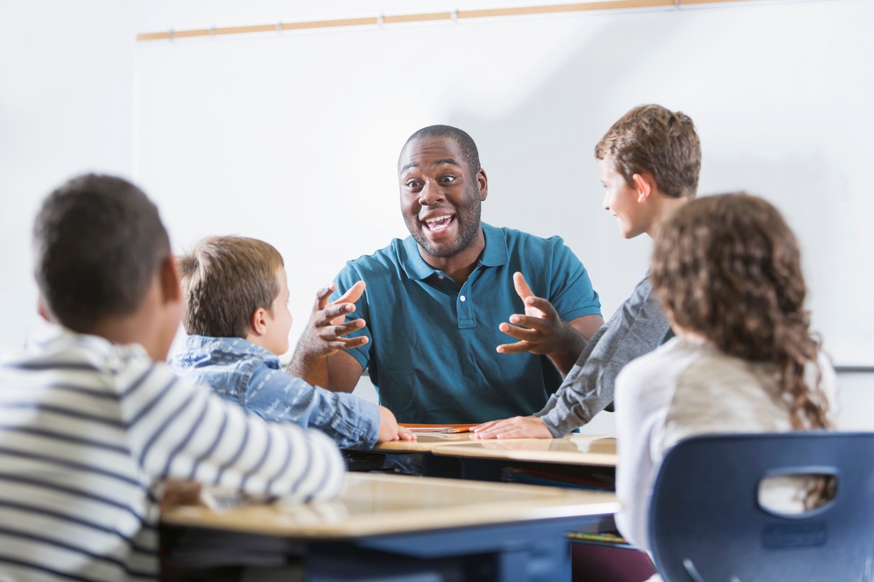 A teacher excitedly talking to four of his students.