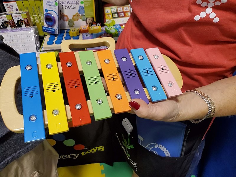 A shopper holding a toy xylophone for kids in a retail store.