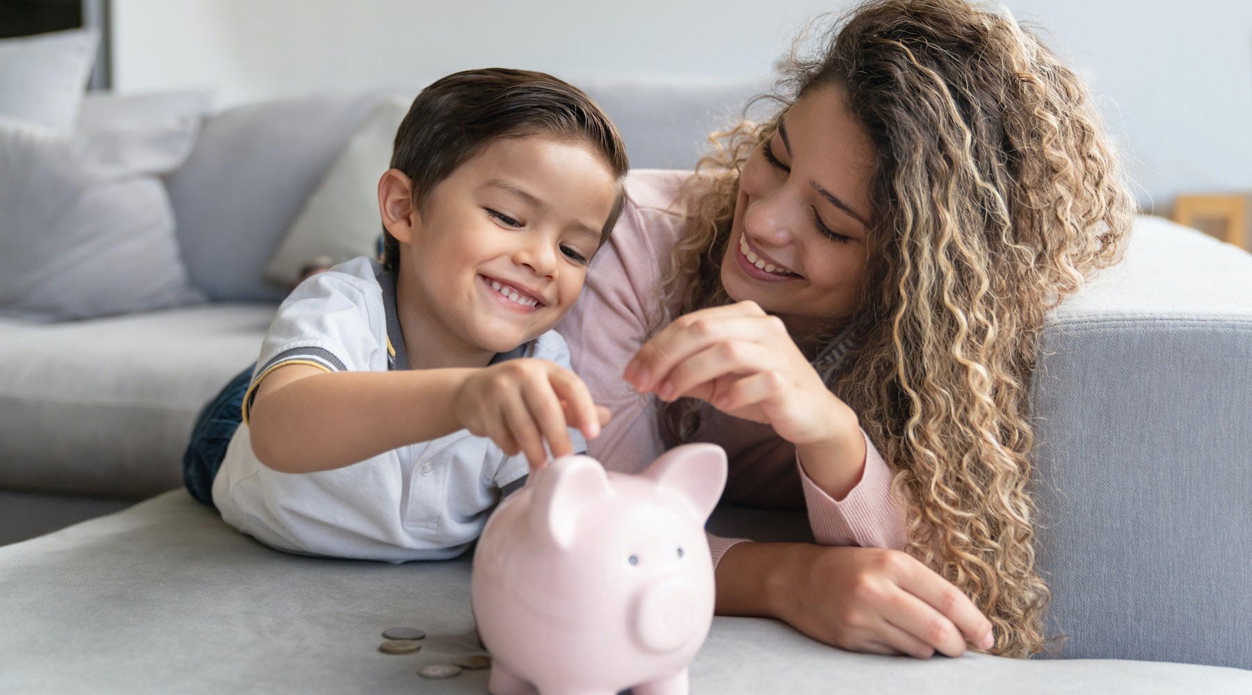 Child putting money in piggy bank with mom.