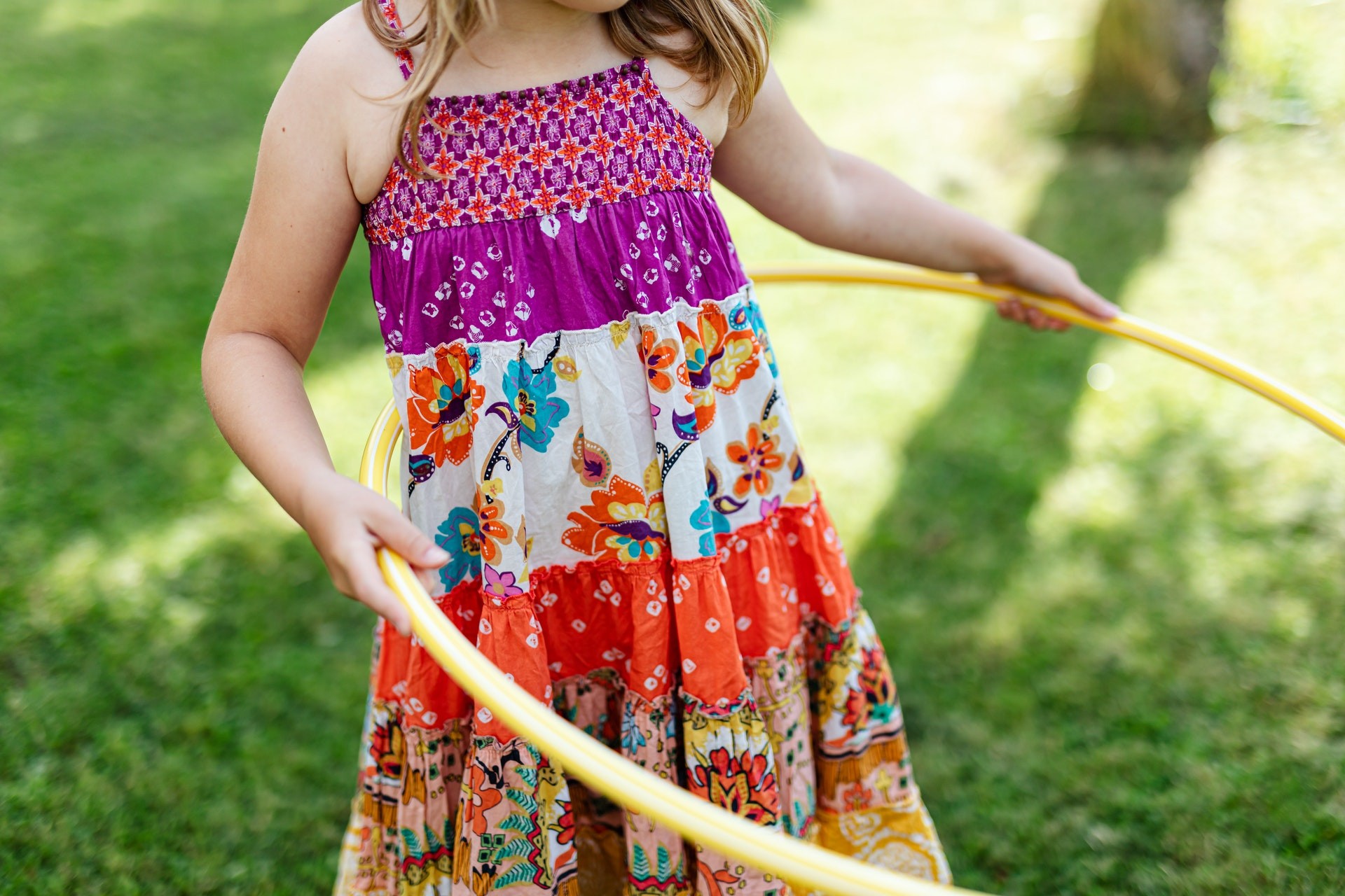 A young student plays with a hula hoop outside.