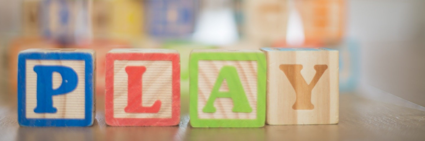 Four wooden blocks spelling out the word "play."