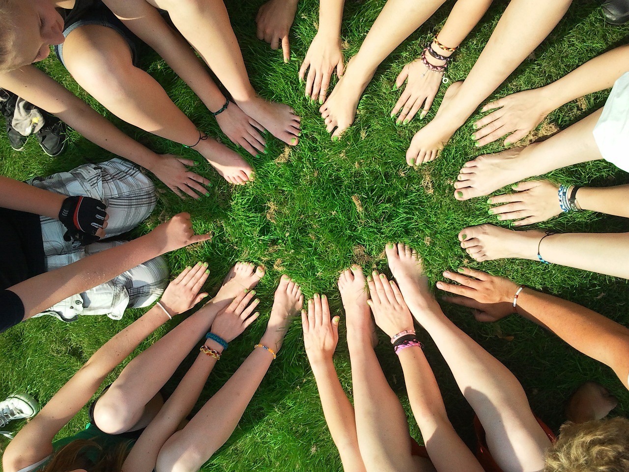 A classroom community sits in a circle with their hands and feet pointed inward.