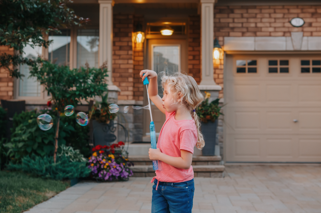 Child blowing bubbles outside during downtime from her homeschooling program