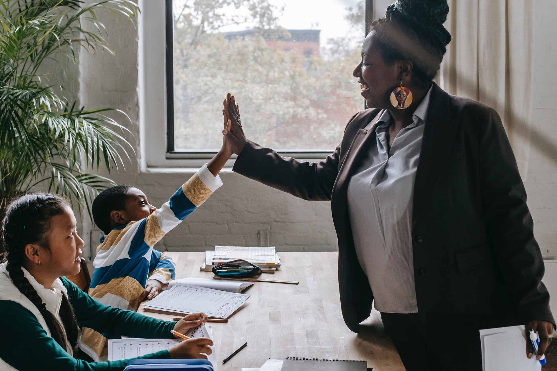 A teacher high-fives a student in her classroom as she teaches elementary math.
