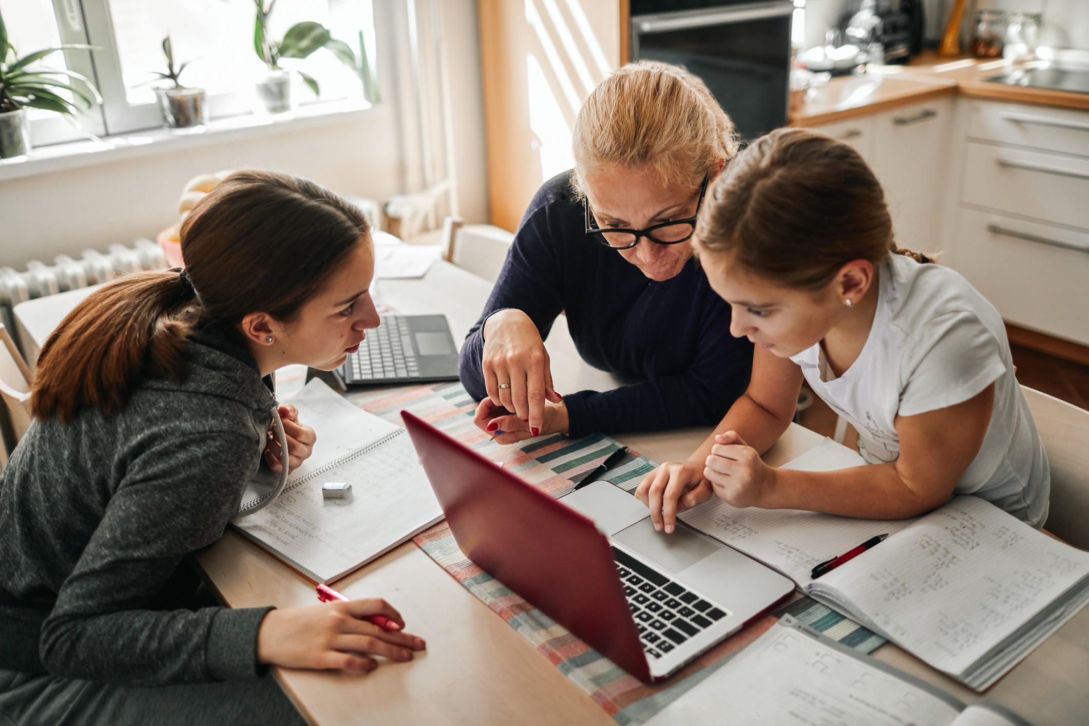 Mother homeschooling her two daughters at their kitchen table
