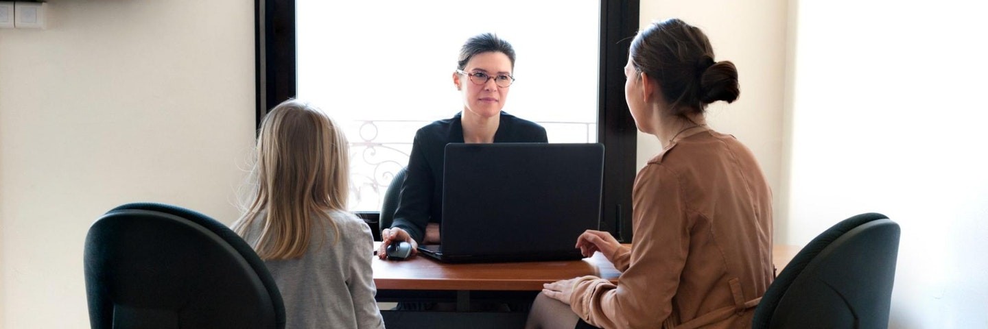 A mother and daughter talk to the child's teacher