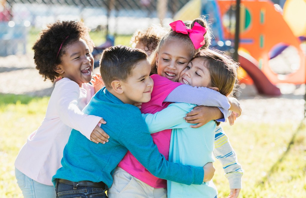 Kindergarten students hugging each other on the playground